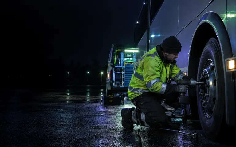 HGV tyre technician working at a lorry wheel at night